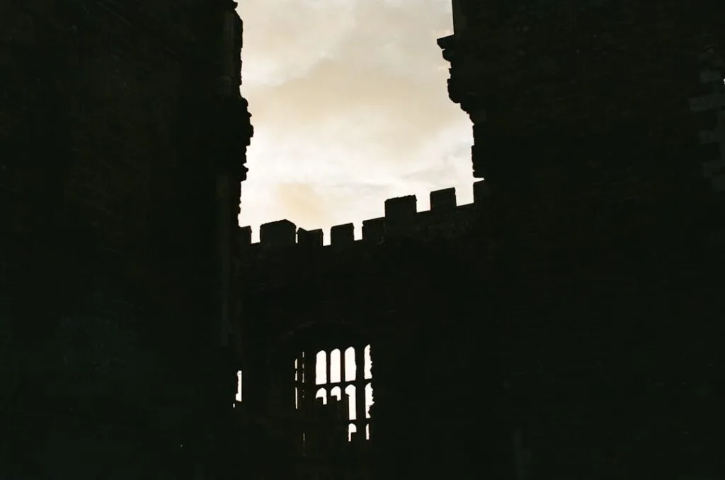 Silhouetted crenellated walls and arched window against dusky sky