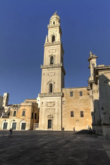 Tall campanile tower rising above empty square in Lecce at midday