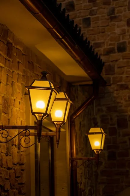 Three glowing street lamps mounted on stone wall in Lecce evening