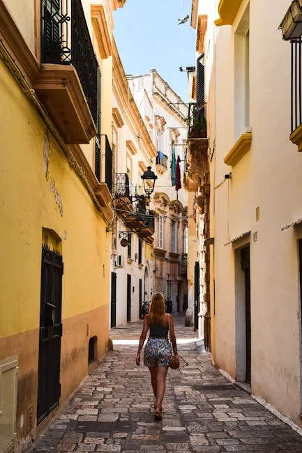 Woman walking down narrow sunlit alley in Lecce's historic center