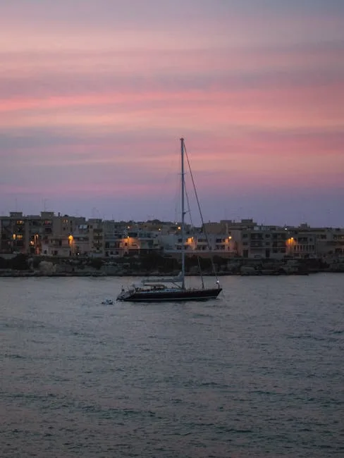 Sailboat anchored off Lecce coastline at pink sunset