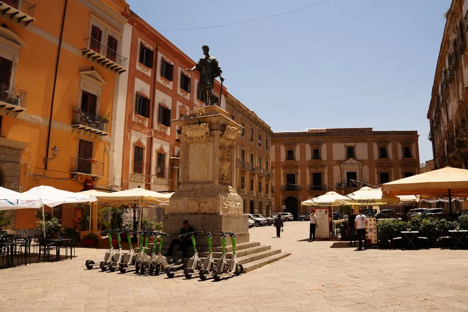 Sunny Lecce square with statue plinth, parked scooters, outdoor cafés