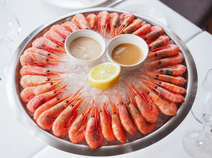 Plate of chilled prawns with lemon and dipping sauces on white tablecloth in Lecce