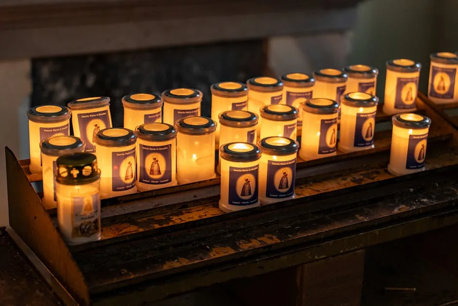 Lit votive candles arranged on metal rack inside church