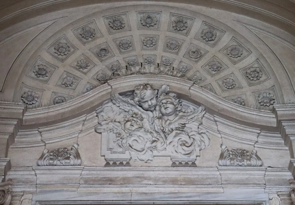 Bas-relief de chérubins en pierre sous une voûte sculptée