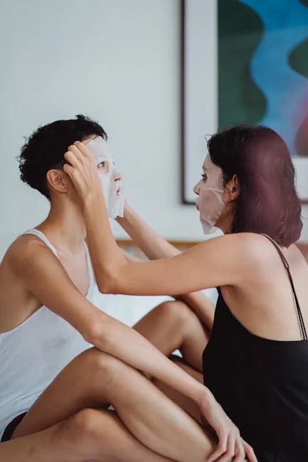 Two people applying sheet face masks together on a bed
