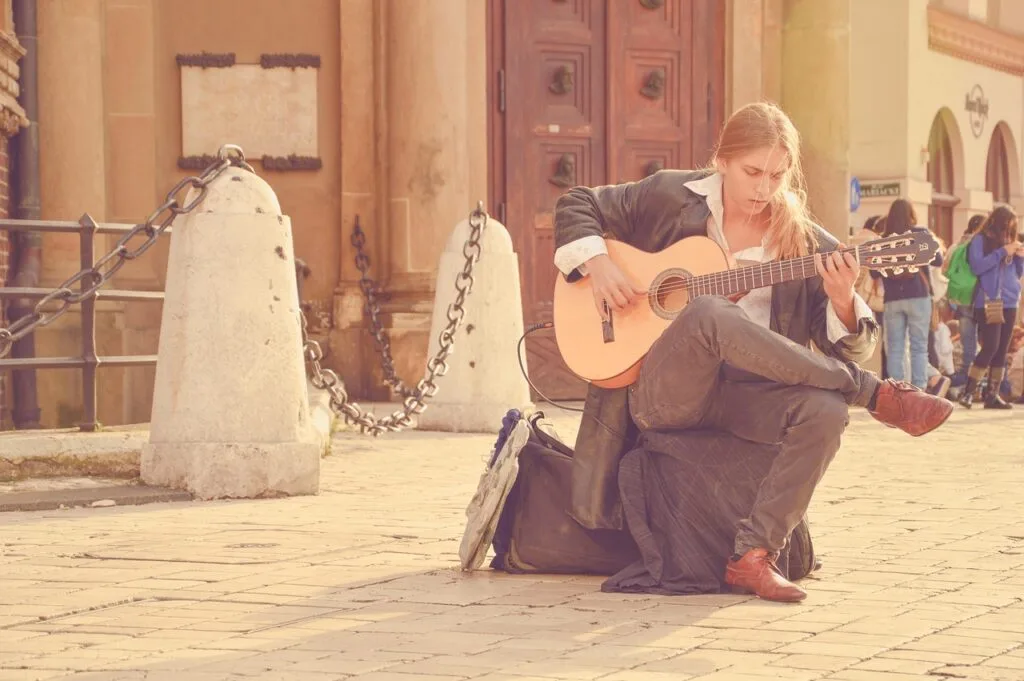 Guitariste de rue assis sur un sac jouant dans une piazza de Lecce
